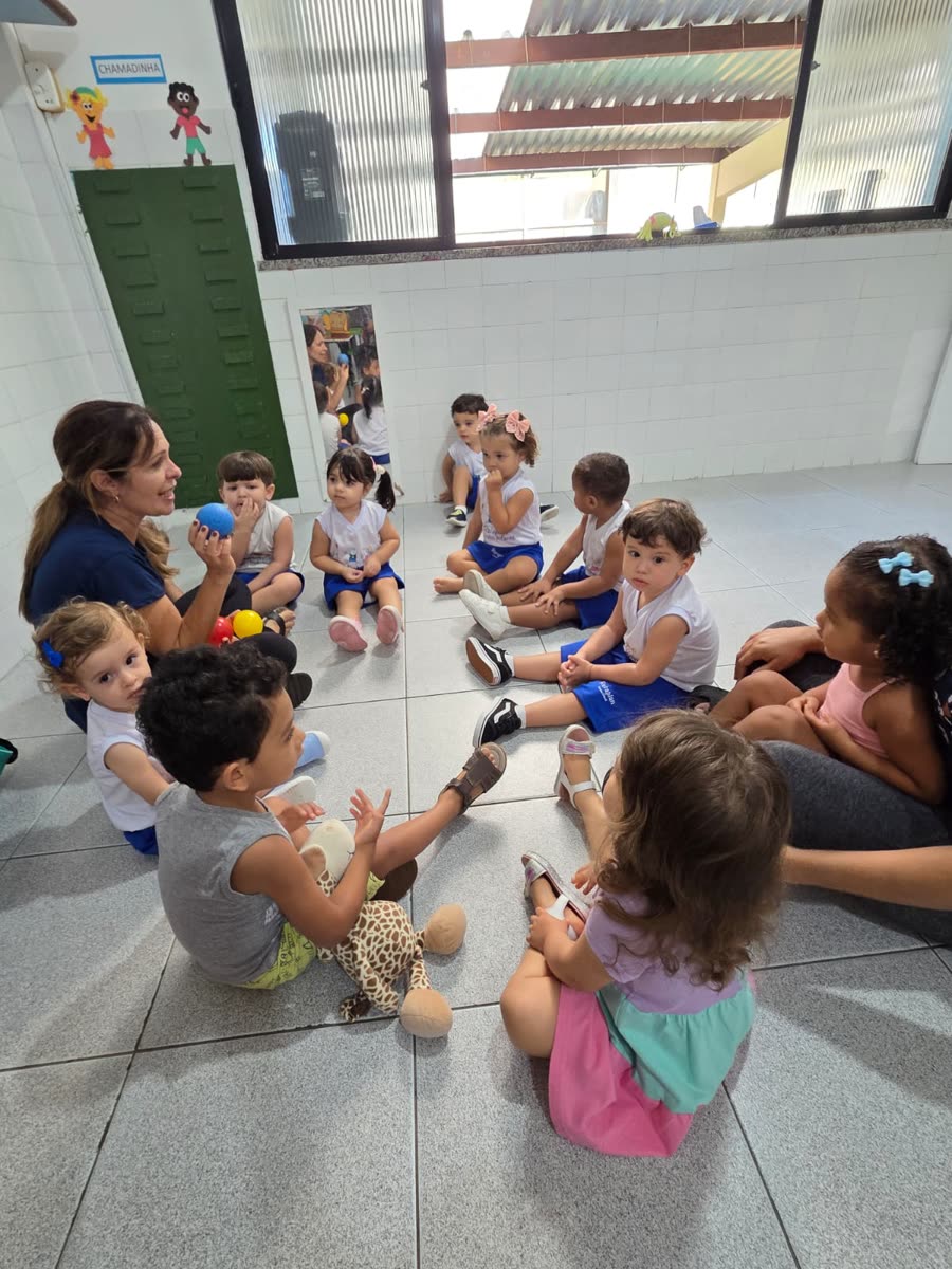 Crianças sentadas em roda brincando com bolinhas coloridas