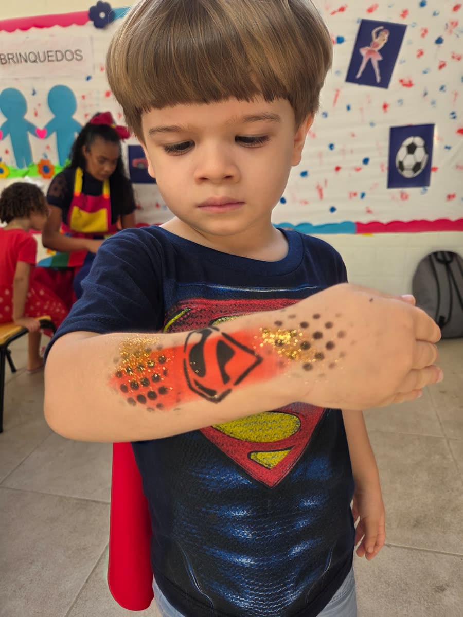 Criança mostrando pintura de super-herói no braço