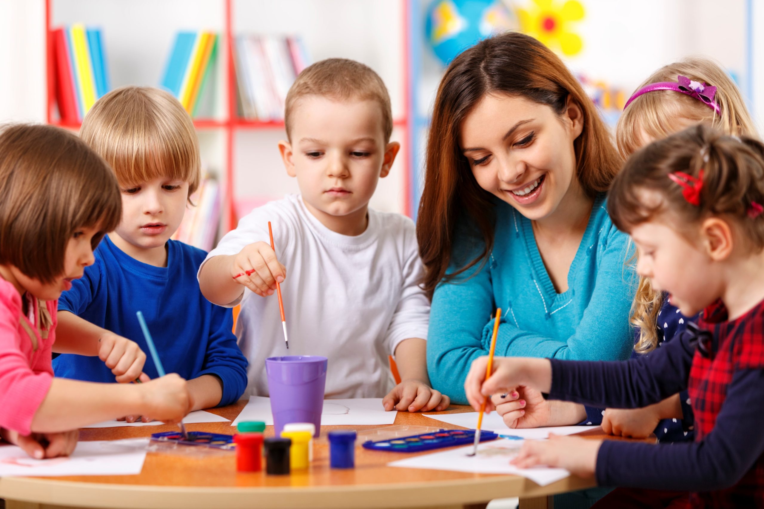 Crianças pintando com a professora em sala de aula da Rataplan